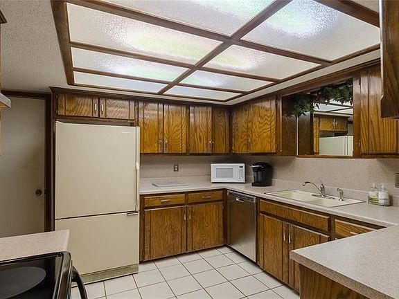 Kitchen with lots of cabinets, stainless stove and dishwasher. Nice cabinet tops, tile floors.