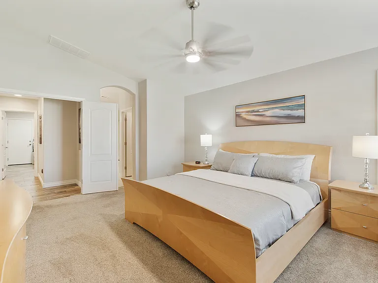 Primary bedroom with King size bed, 2 nightstands, armoire, dresser, fan, chair, tv and entrance to ensuite