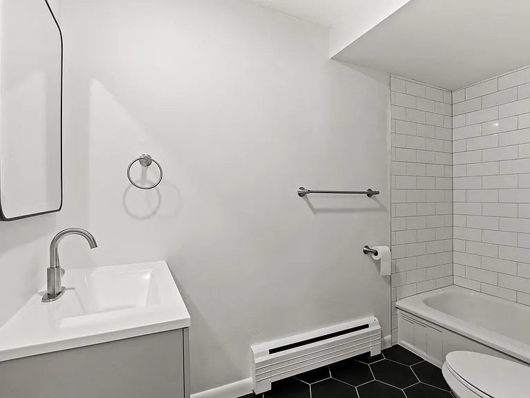 Modern bathroom featuring a sleek white vanity, chrome fixtures, and a stylish tiled bathtub.