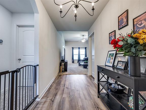 Hallway featuring arched walkways, wood finished floors, and a chandelier