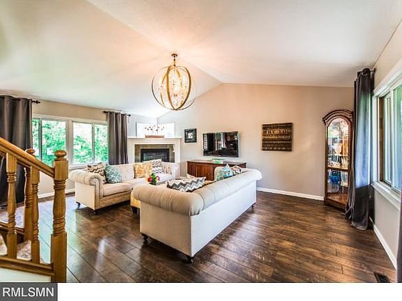Foyer and living room with beautiful fireplace and gorgeous wood floors and beautiful light fixture.