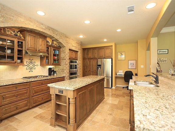 Gorgeous Island kitchen with granite counter top, brick surround, gas cook top, tons of custom cabinets! Kitchen overlooks family room!