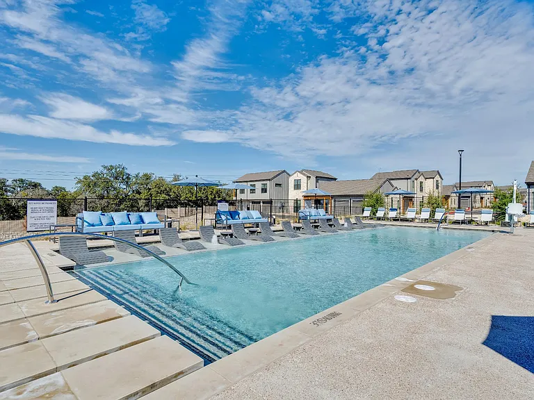A sunny day at the outdoor pool with blue water and sun loungers.