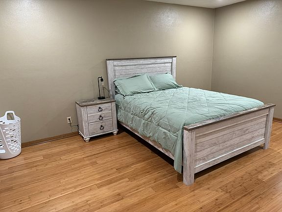 large bedroom with queen bed, bedding, nightstand, dresser and large closet