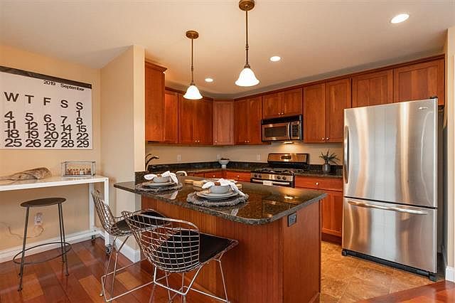 Kitchen with granite counters, steel appliances and breakfast bar.