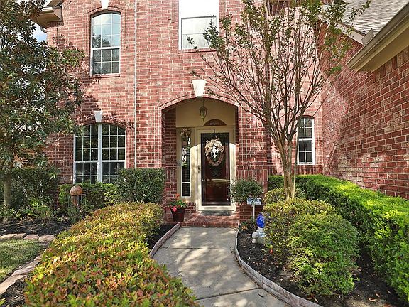 Winding walkway leads you to an arched brick porch with limestone keystone accent, storm door and outdoor chandelier.