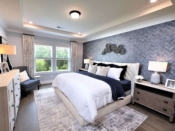 The spacious primary suite offers tray ceilings, large windows, and a walk-in closet.