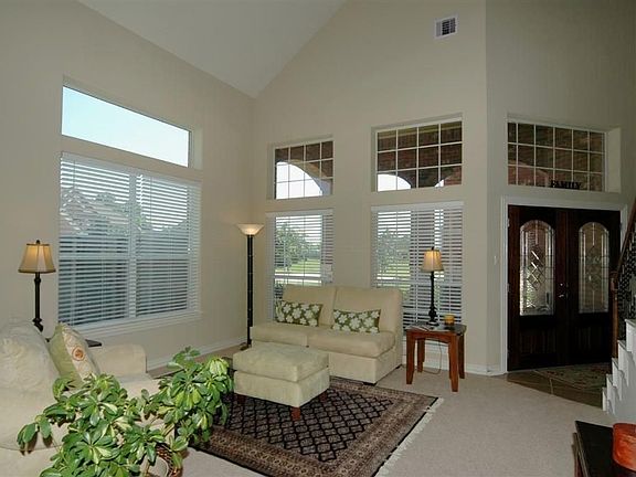  Leaded glass double doors open to a tile floor, soaring ceiling, transom and staircase with wrought iron balusters. Open, two story living room makes for an exceptional greeting area.