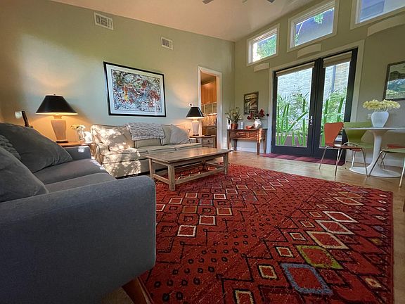 The living room has a couch and love seat and picture windows.