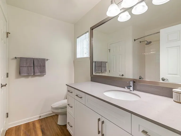 Renovated Package II bath with white cabinetry, grey quartz countertop, and hard surface flooring