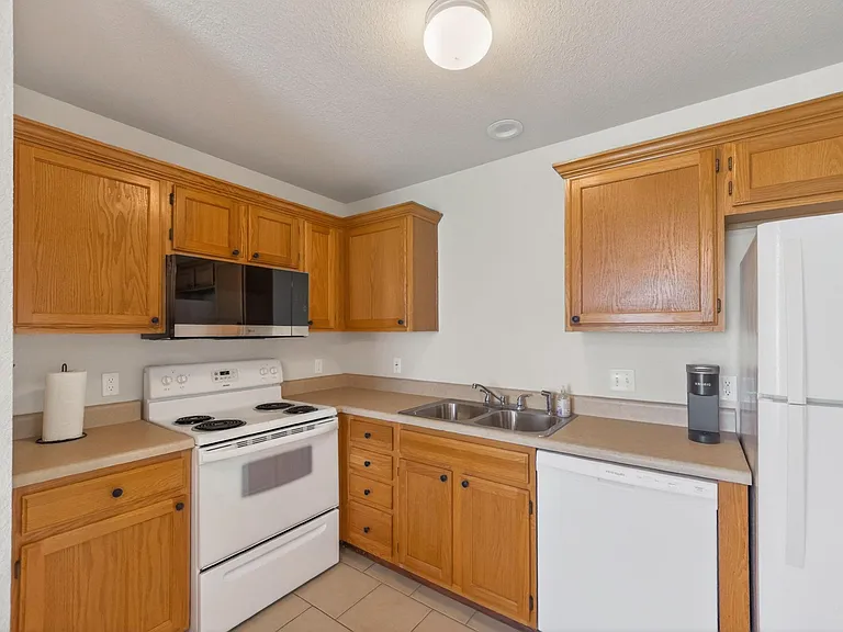 U-shaped kitchen with ample wood cabinetry, laminate counters, and a double-basin sink plus range, microwave, and fridge.
