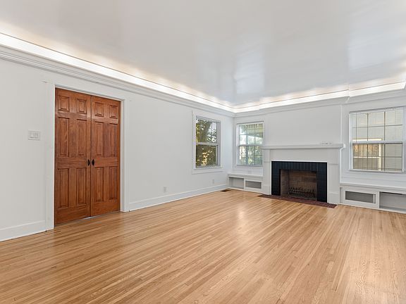 Beautiful living room with working wood burning fireplace, built in window seats, and original hardwood flooring.