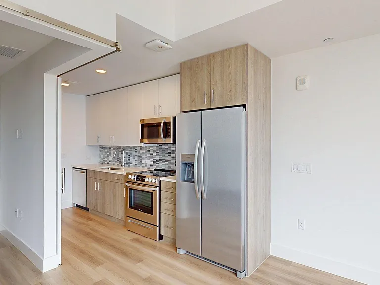 Apartment Kitchen with Stainless Steel Appliances, Quartz countertops and Wood-Style Flooring.