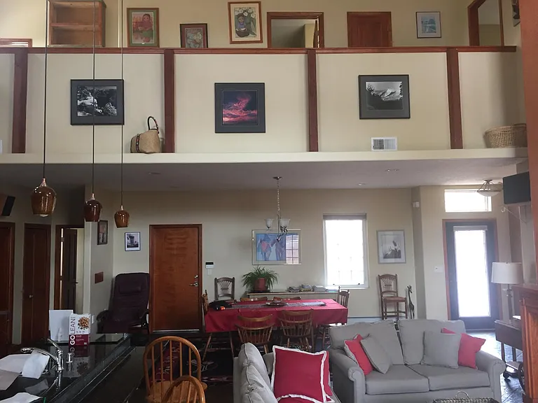 Living room view toward dining, 1/2 bath, and upper floor walkway.