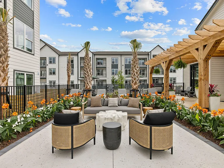 Luxury apartment outdoor lounge with poolside seating, lush landscaping, and resort-style community amenities.