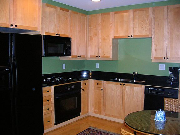 Kitchen has blk granite, stained cabinets, black appliacnes & hardwood floors 