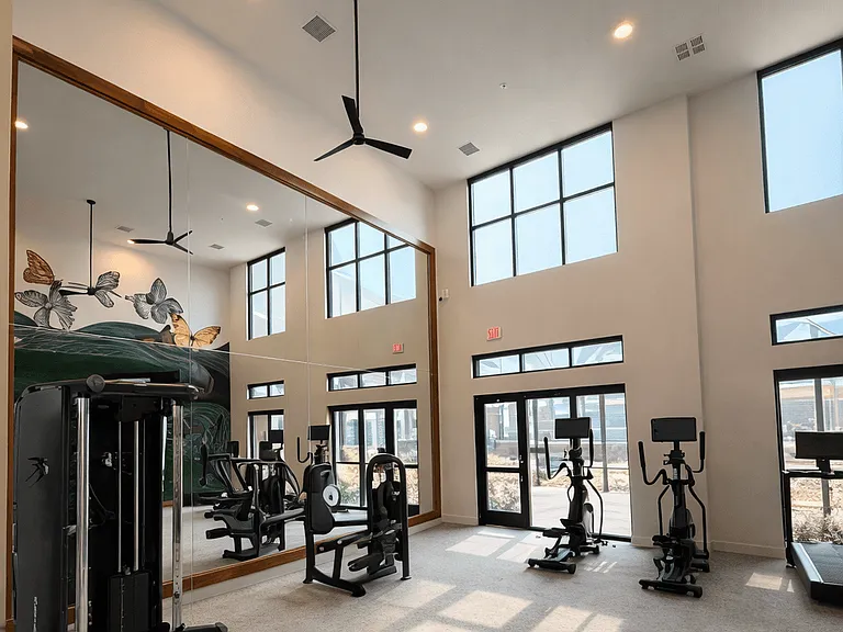 A bright, spacious fitness center designed for both cardio and strength training, featuring high ceilings, natural light, and modern equipment.