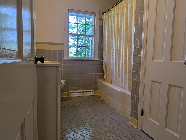 Main bathroom, original tiles in excellent condition, cast iron tub, large closet storage.