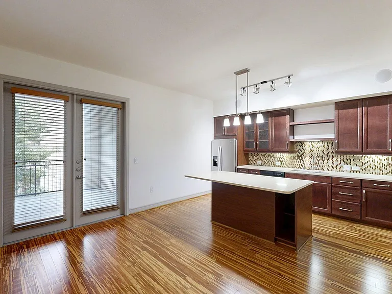 Apartment Kitchen with Stainless Steel Appliances, Dining and Living Room with Wood-Style Flooring and Patio/Balcony.