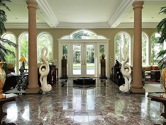 Stately columns & a wall of impressive arched windows accent this stunning open great room. Double glass doors allow direct access to the park-like grounds & impressive marble flooring flows through this entire area. Entertainer's dream come true!