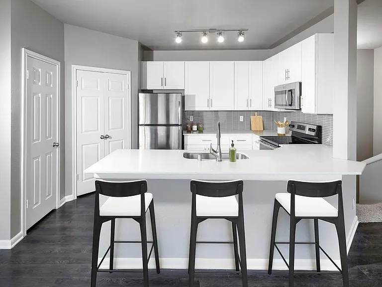 Classic Package II kitchen with stainless steel appliance, white quartz countertop, tile backsplash, white cabinetry, and hard-surface flooring