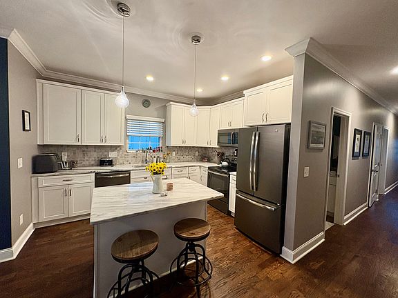 Kitchen and hallway that leads to full bath, laundry room and downstairs bedroom and back door.