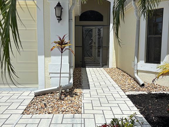 Entrance with mature landscaping, mulch, irrigation, combo door lock on front door screen entrance.