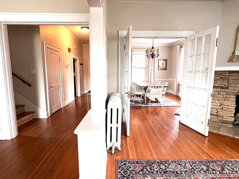 View from front door, primary living room on the left, secondary living room on the right, seeing into the dining room half bath & kitchen down the hall to the left.