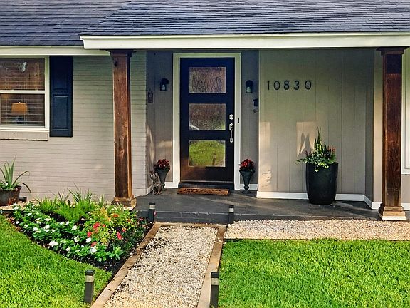 FRONT ENTRY: Clever use of white crushed rock and concrete for the sidewalk and tidy front porch perfect for potted plants. Colorful flower beds flank the front porch with the natural cedar columns.