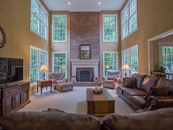 The sunk-in two-story Great Room with a two-story masonry gas fireplace offers scenic greenery views and amazing natural light.