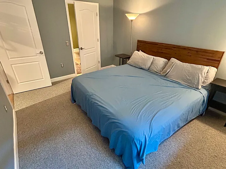 Newly carpeted and painted bedroom overlooking the private balcony featuring a king-size bed with plenty of space for an armoire or workspace.