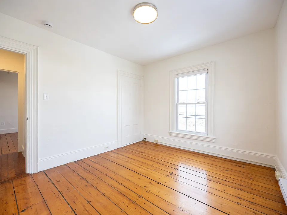Second bedroom with hardwood floors and natural light