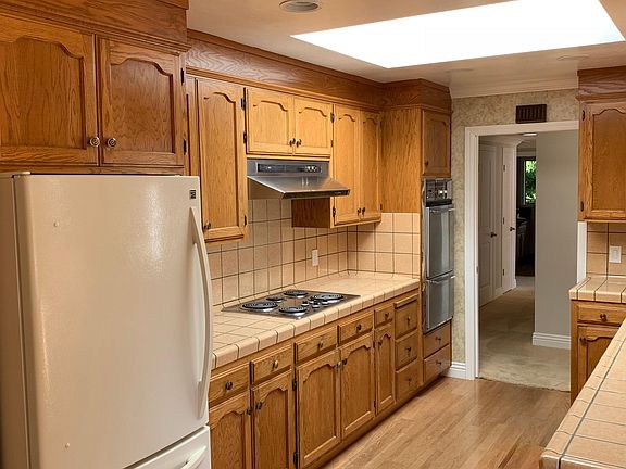 Large kitchen with oak cabinets, tiled counters and large skylight to brighten.