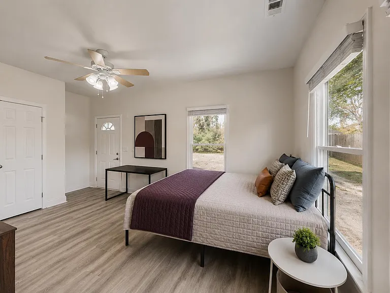 Spacious bedroom with large windows, ceiling fan, wood-style floors, and a closet for convenient storage.