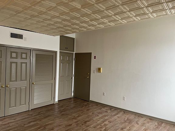 Living room looking back at entrance. Tin ceilings throughout with vinyl plank flooring