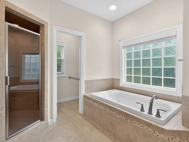 Primary walk-in shower with dual shower heads, soaking tub and private water closet
