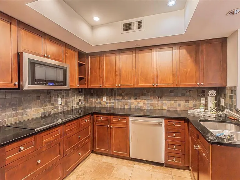 U-shaped kitchen with wood cabinetry and dark countertops