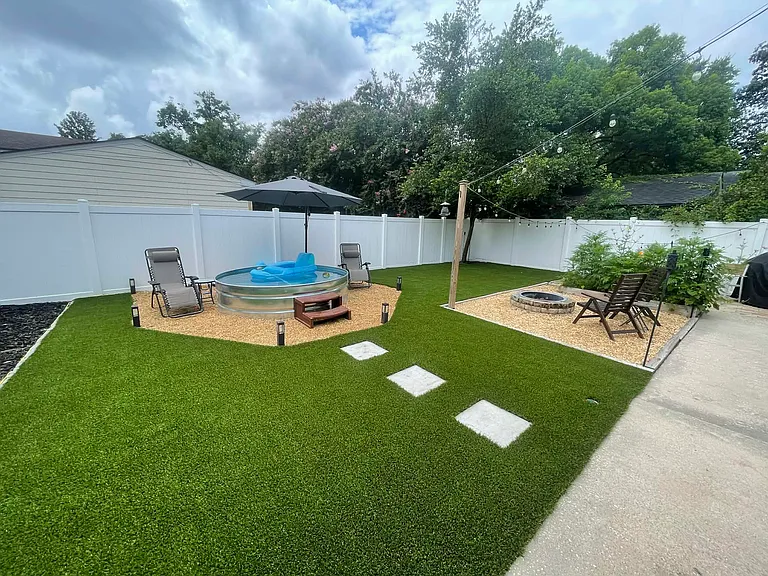 Welcoming backyard with turf, a fire pit, string lights, and grill area. New mulch all along the side of the home and an abundance of outdoor storage. Must see