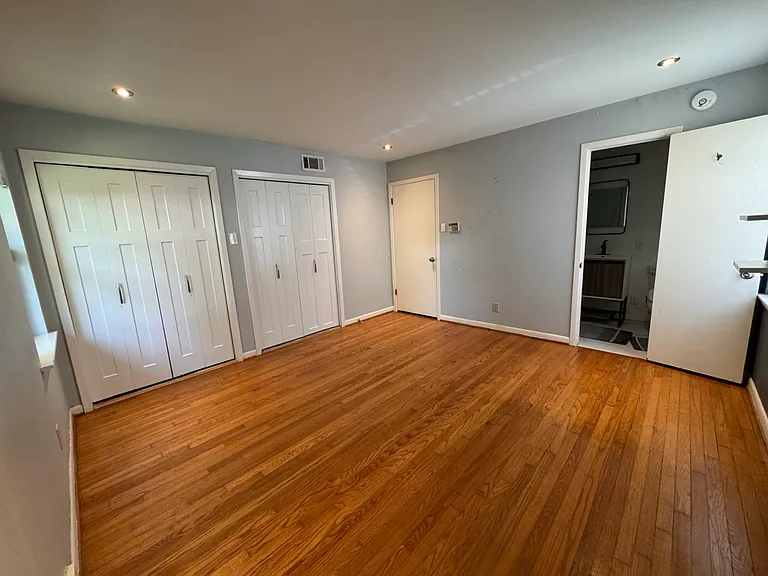 Spacious primary suite featuring immaculate original hardwood flooring, modern recessed lighting, and dual closets. This entire space is currently getting a premium, fresh coat of paint to perfectly match the newly renovated private en-suite bathroom.