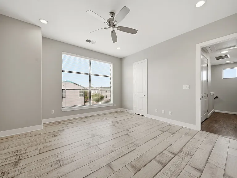 Bright and spacious primary suite featuring modern wood-look flooring, soft neutral tones, and a large window that fills the space with natural light. Designed for comfort and relaxation, this inviting retreat offers a clean, contemporary feel.