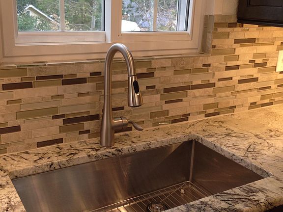 Oversized stainless steel sink, tiled back splash and undercabinet lighting.