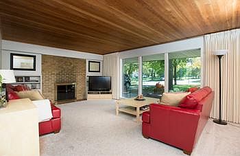 Spacious Living Room with large windows, gas log brick fireplace, built in shelving, accent lighting and Pinewood ceiling.