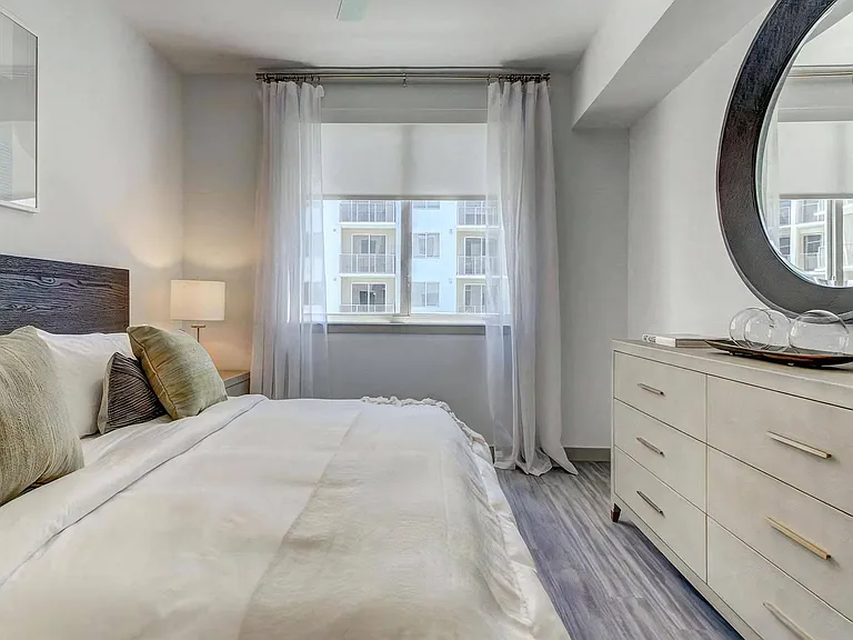 Queen Bed With Neutral Bedding and Large Window Allowing Ample Natural Light
