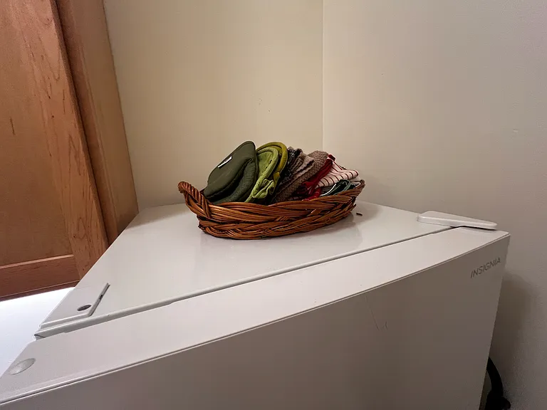 More linens and potholders on top of refrigerator.