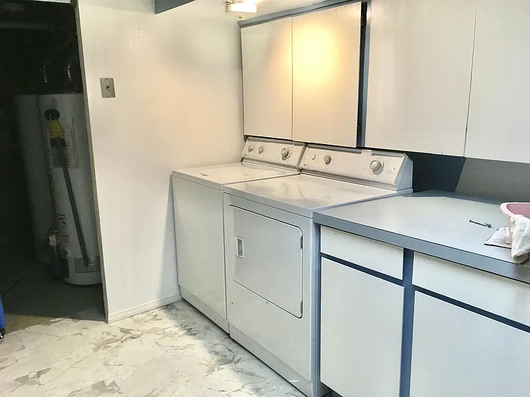 The laundry room is also the third bathroom, with a shower, toilet, and large utility sink on the other side of the room. The water heaters in the background are in a storage room with shelving. There's lots of space not shown in the photo. W/D not inc