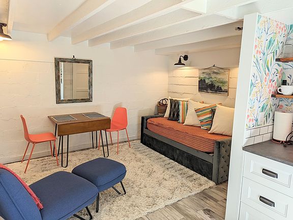 Main living space with daybed, dining table with drop leaves that can seat 2-4 people, comfy chair with ottoman.