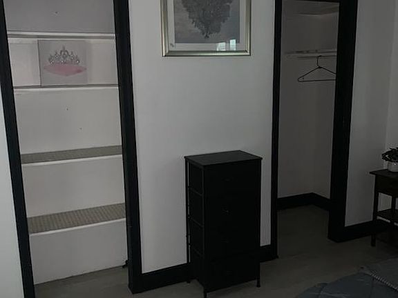 Bedroom area with dual open closets, built-in shelving, and space for a dresser to keep belongings organized.