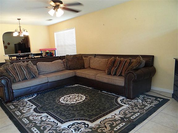 This welcoming and spacious living room/dining room combo has allergy friendly tile floors, cooling ceiling fan an elegant chandelier, neutral walls, sunny windows, and even this oversized sectional fits perfectly in here!