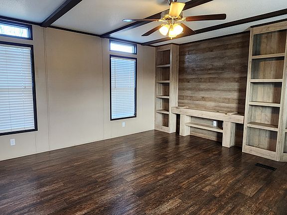 Spacious den features book cases, entertainment center, rich dark colors and tall windows for natural light.