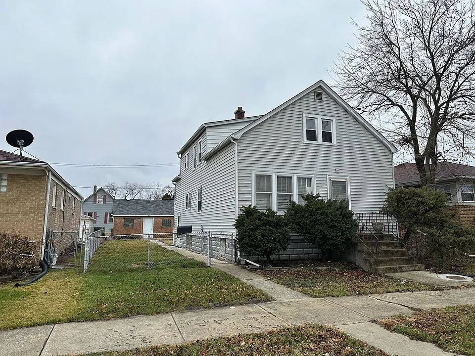 Front of house with a double lot and fenced in yard.